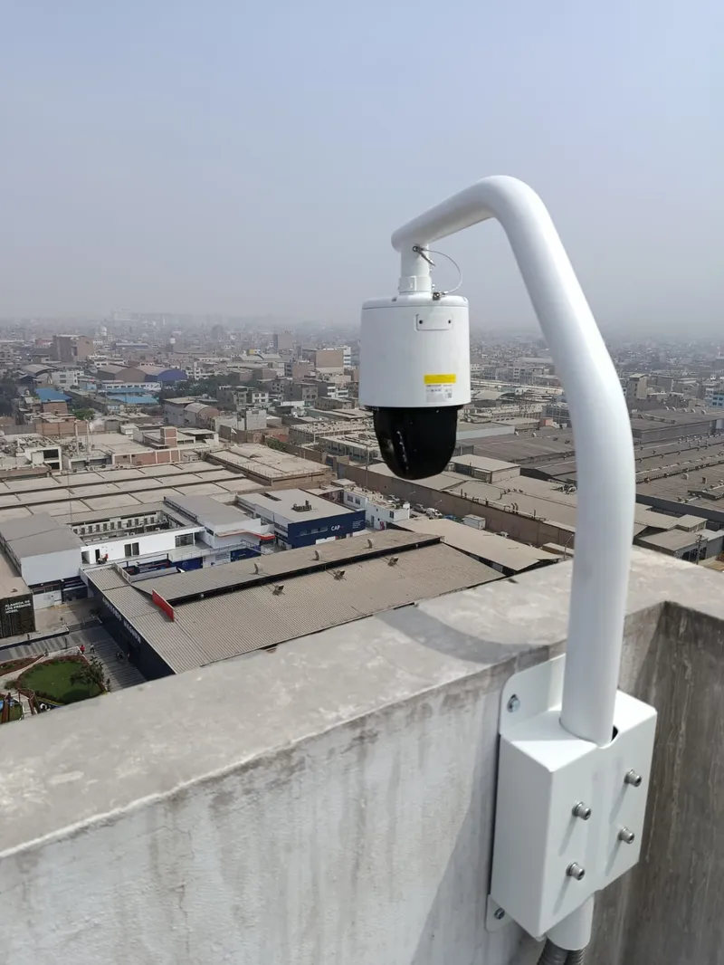 Cámara PTZ montada en borde de edificio con panorámica de Lima al fondo