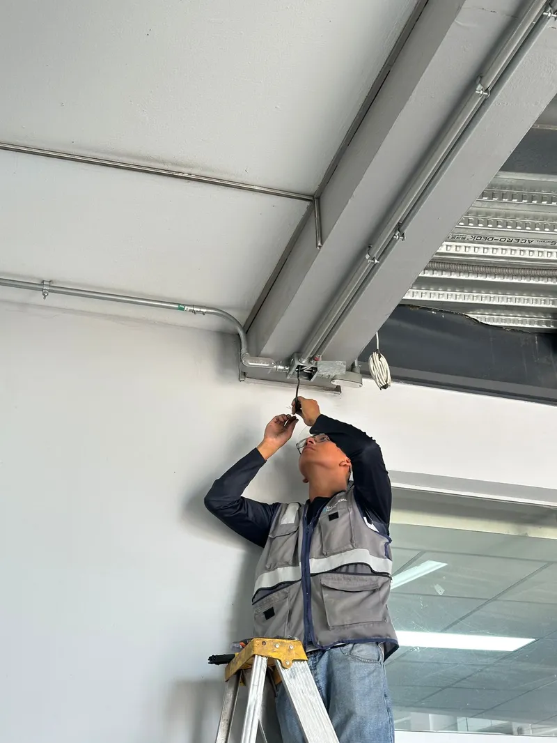 Técnico instalando canaleta metálica en techo de local comercial