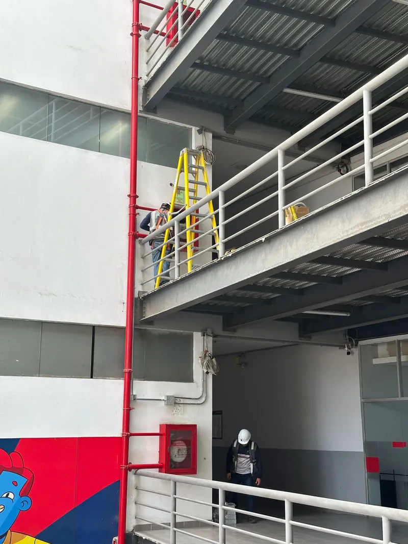 Técnico instalando cámara en pared exterior con nivel láser y herramientas